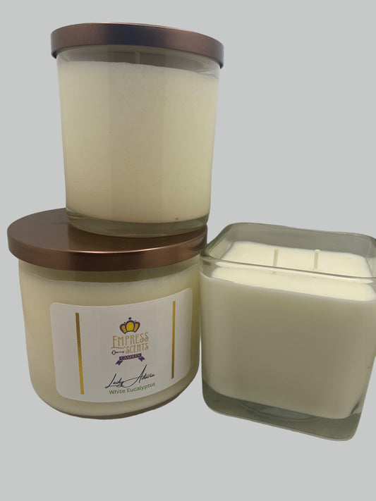 two cylindrical candle jars with white candle wax, one cube-shaped candle jar with white candle wax