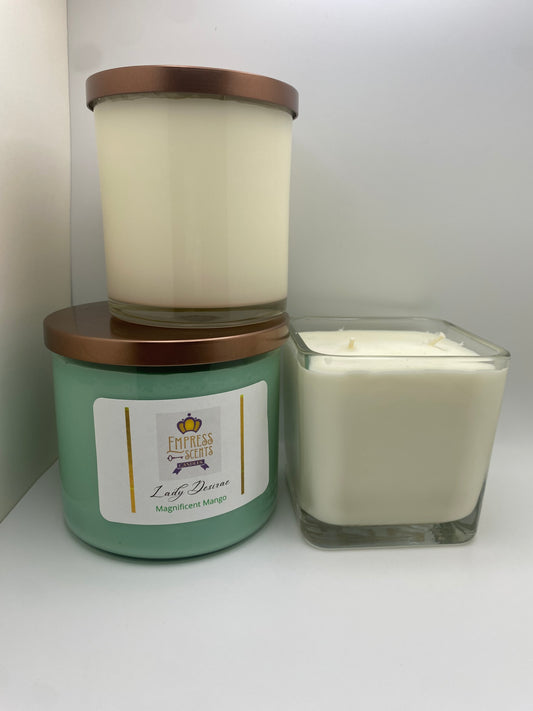 one cylindrical candle jar with white candle wax, one cylindrical candle jar with light green candle wax and one cube-shaped candle jar with white candle wax