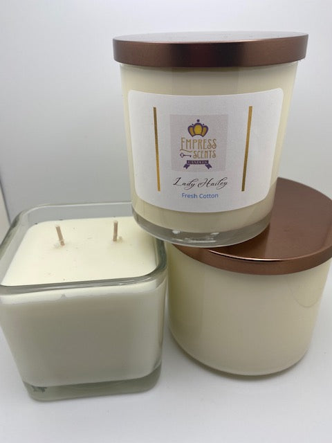 two cylindrical-shaped candle jars with white candle wax and one cube-shaped candle jar with white candle wax