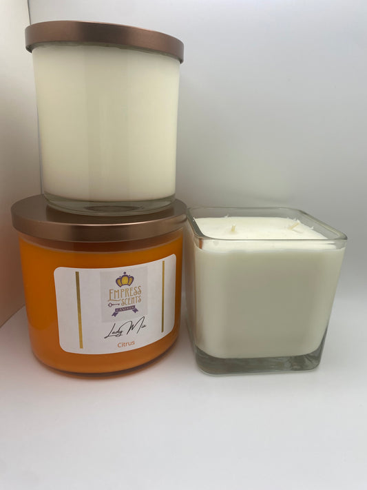 one cylindrical candle jar with white candle wax, one cylindrical candle jar with orange candle wax and one cube-shaped candle jar with white candle wax