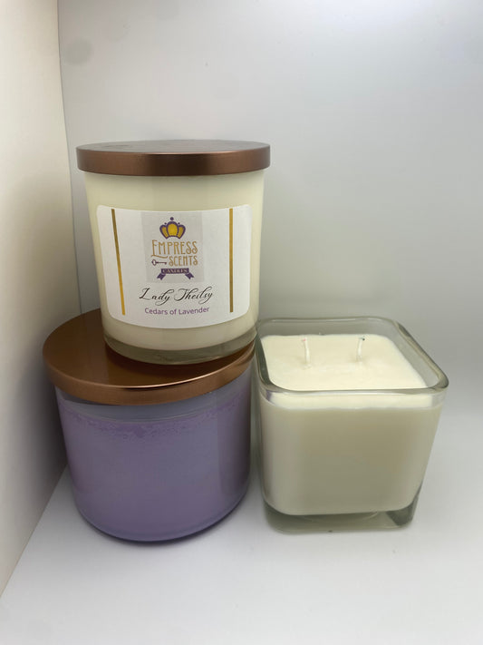 one cylindrical candle jar with white candle wax, one cylindrical candle jar with lavender-colored candle wax and one cube-shaped candle jar with white candle wax