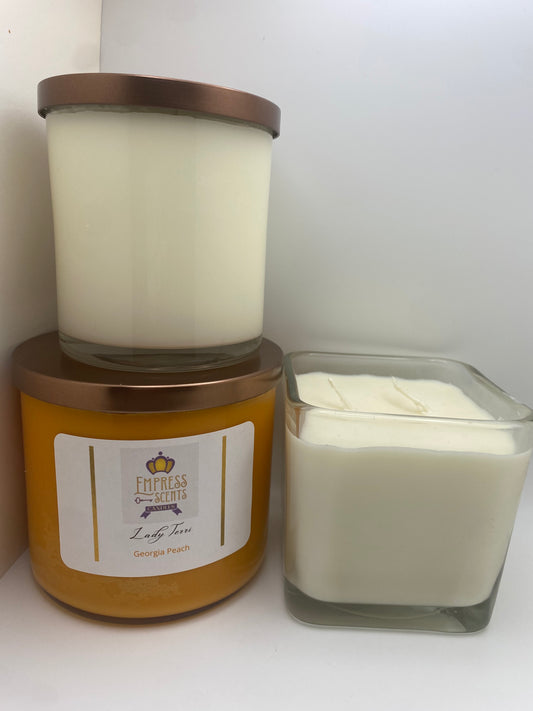 one cylindrical candle jar with white candle wax, one cylindrical candle jar with orange candle wax and one cube-shaped candle jar with white candle wax