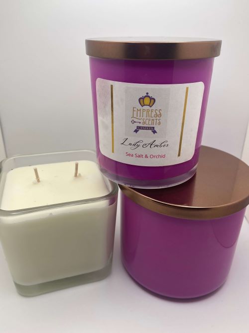 two cylindrical candle jars with purple candle wax and one cube-shaped candle jar with white candle wax